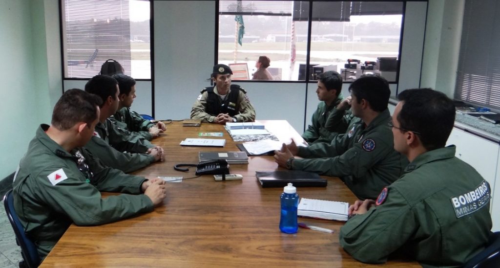 Ten Cel Ledwan Salgado Cotta, cmt do Btl RpAer, ao centro realizando um briefing com os 7 militares do CBMMG que irão participar do programa de treinamento.